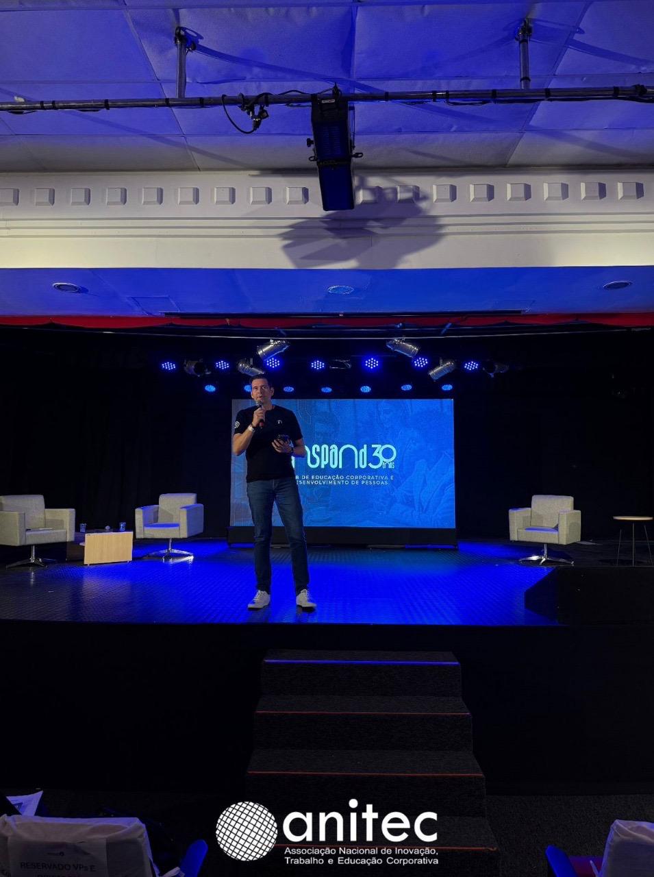 Cristiano Franco palestrando no palco com a marca Inspand e identificação da Anitec